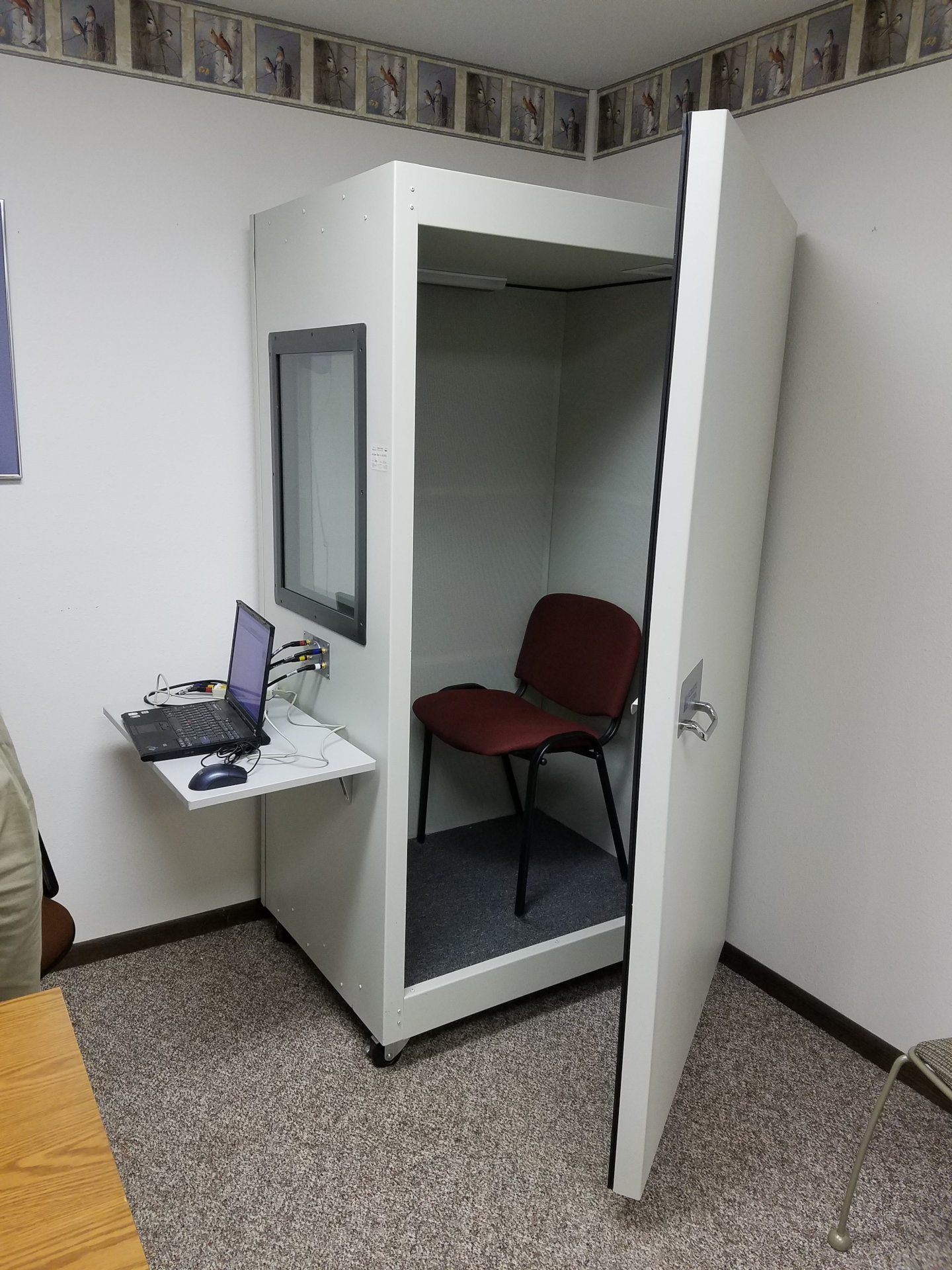hearing test booth with door ajar and laptop hooked up outside